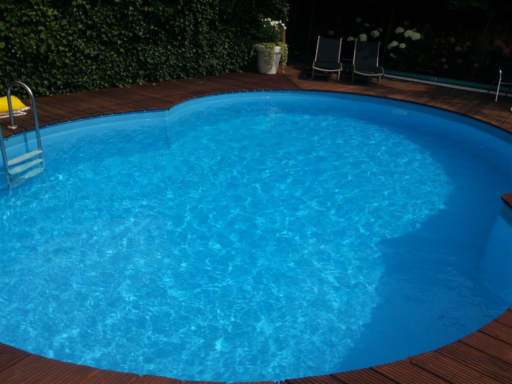 Nierbad met bruine houten vlonder, trapje en heldergeblauw water, met een groene haag erachter in Soest.