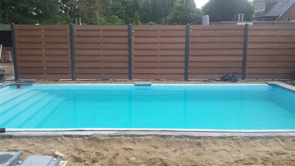 Gevuld bassin met nieuwe lichtblauwe folie en trap, voor een houten schutting in Soesterberg.