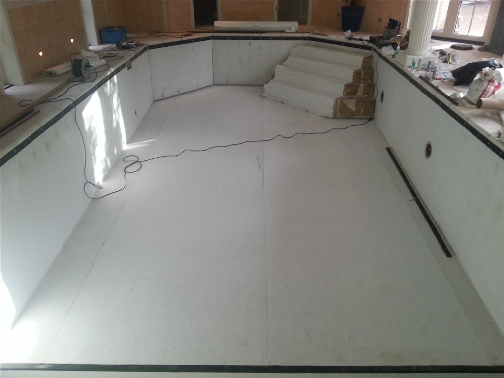 Bassin volledig bekleed met witte onderlaag, klaar voor de blauwe folie, trap aan de kopzijde.