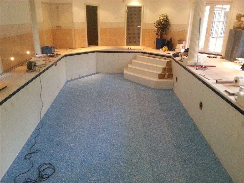 Bassin met blauwe folie op de vloer en witte wanden, trap aan de kopzijde nog wit.