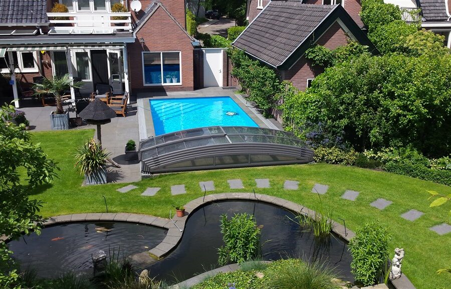 Achtertuin in Soest met vernieuwd buitenbad, overkapping, palmen en een grote vijver op de voorgrond