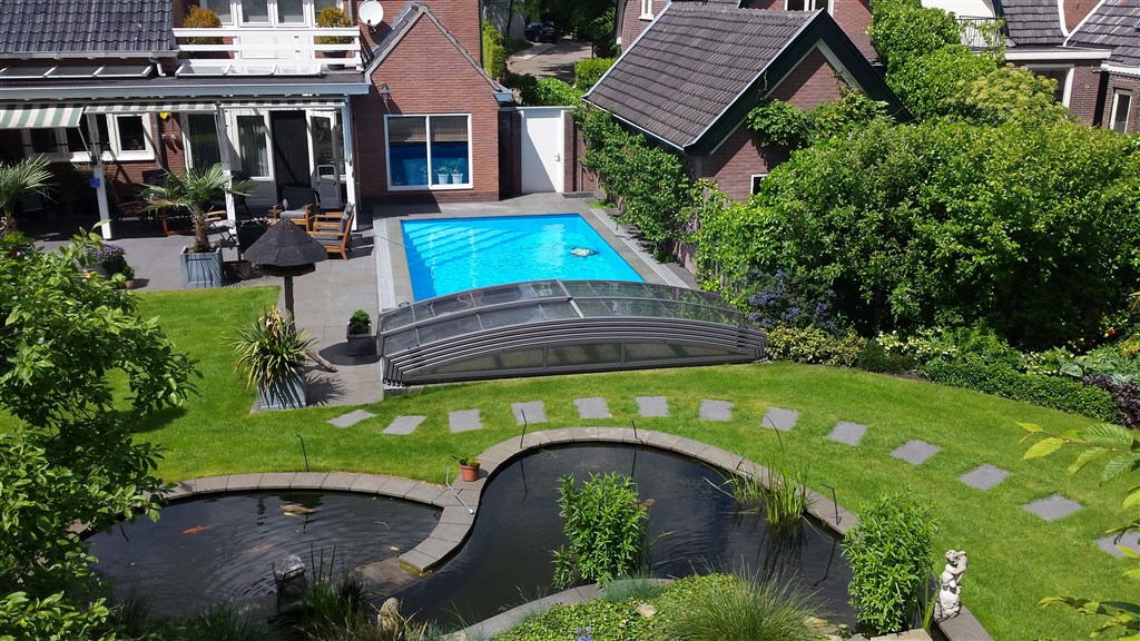 Achtertuin in Soest met vernieuwd buitenbad, overkapping, palmen en een grote vijver op de voorgrond