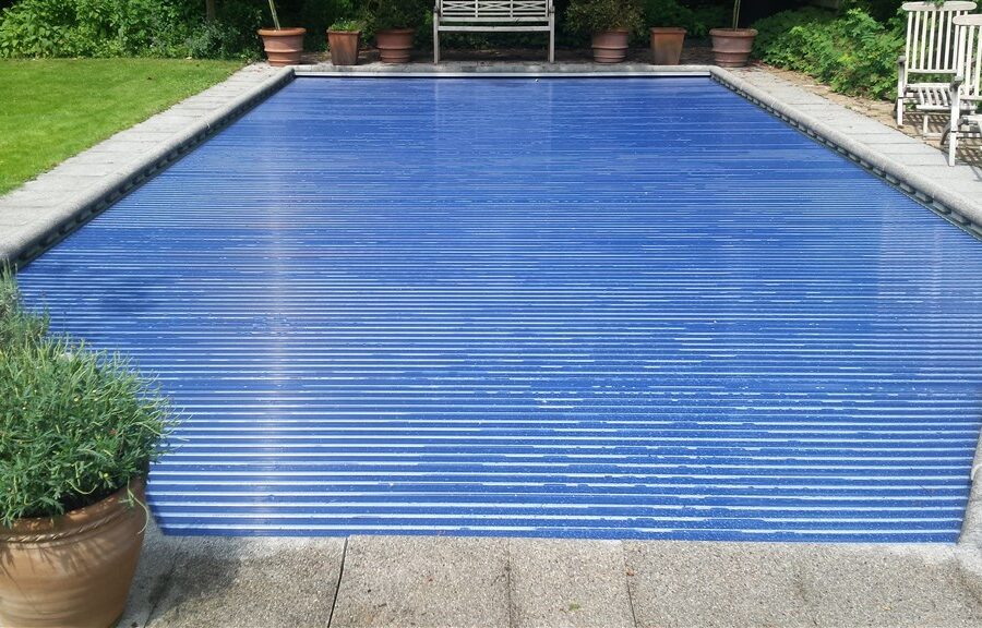 Blauwe solar-lamellenafdekking over het zwembad, gezien vanaf de kopse kant met terracotta potten in Zeist.
