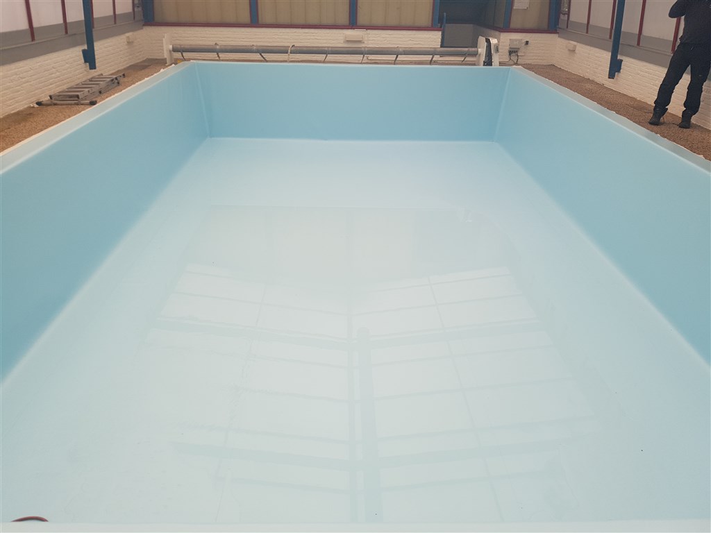 Leeg bassin met nieuwe lichtblauwe folie op wanden en bodem, binnen in de hal.