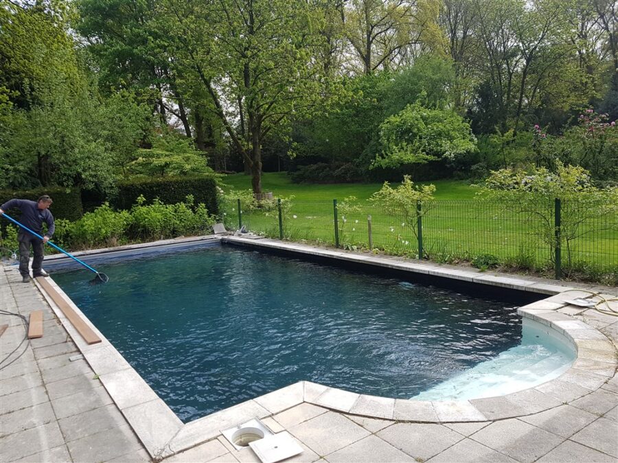 Gerenoveerd buitenbad met donkere folie en ronde trap in een groene tuin in Laren.