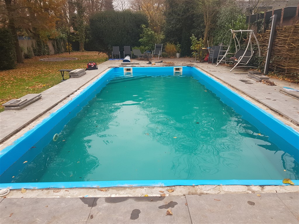Bassin met nieuwe blauwe folie en groenblauw water, gezien vanaf de korte kant.