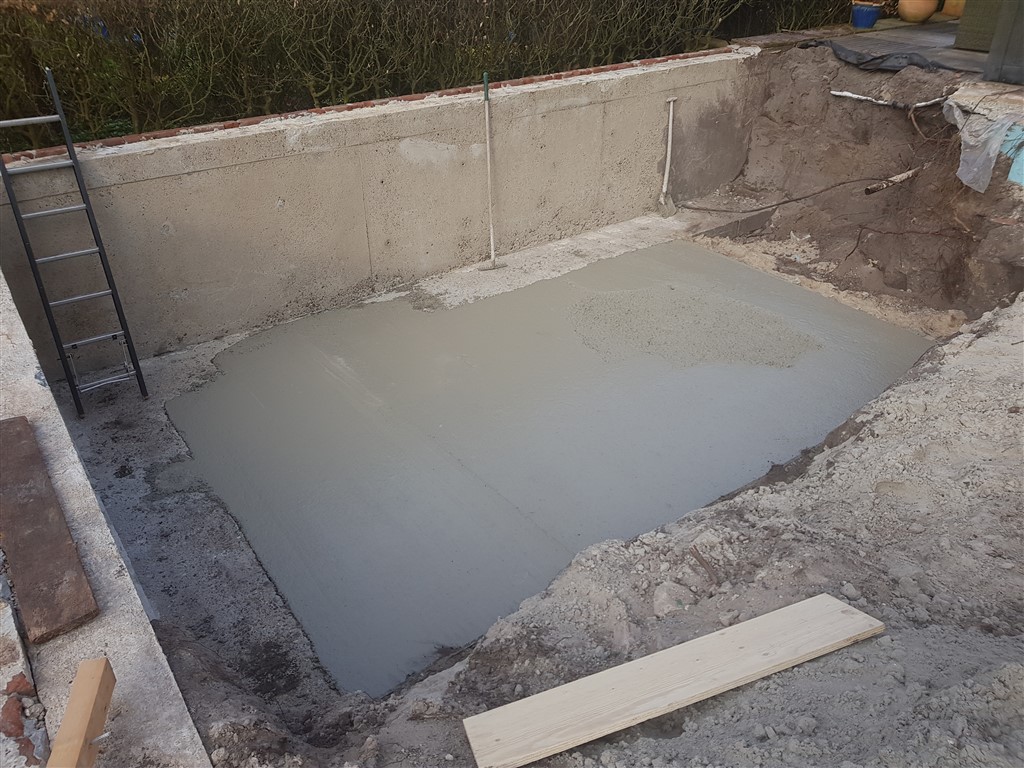 De gestorte betonvloer in hetzelfde bassin, met de ladder nog tegen de wand.