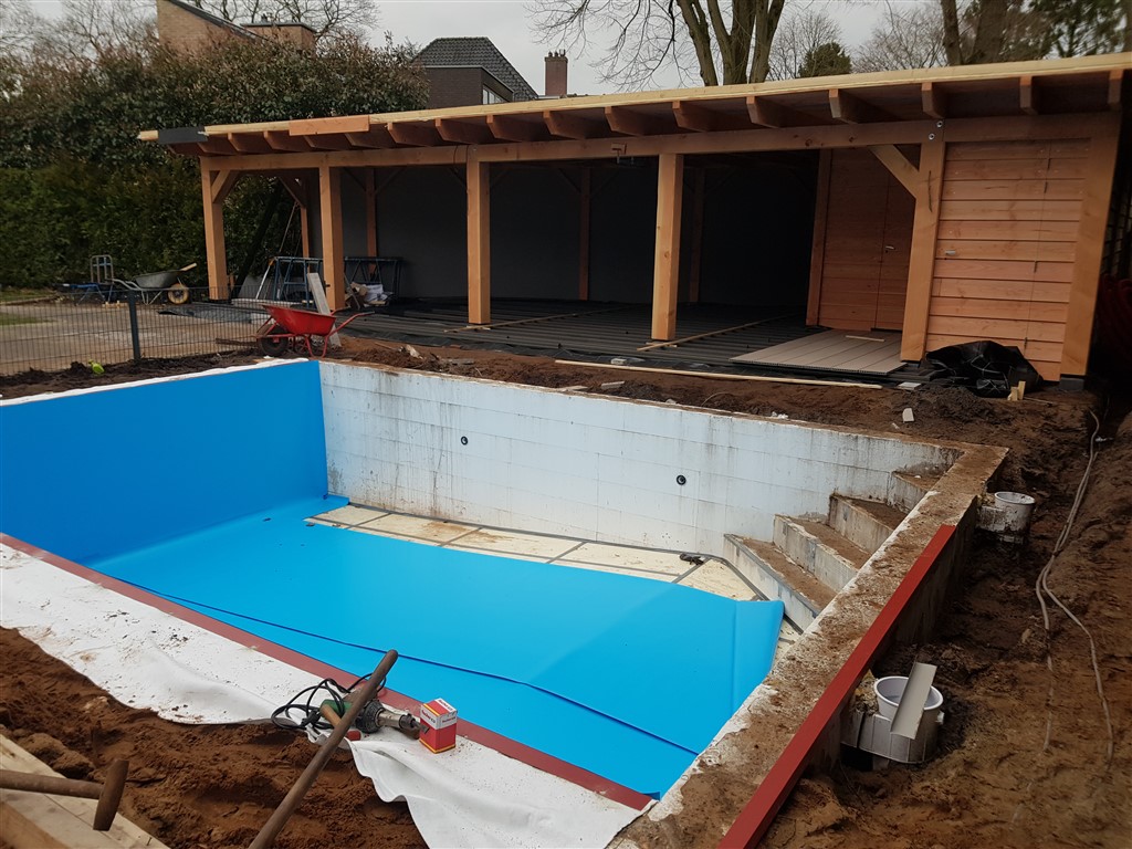 Blauwe folie ligt nu ook op de bassinvloer, naast de trap, voor het houten bijgebouw.
