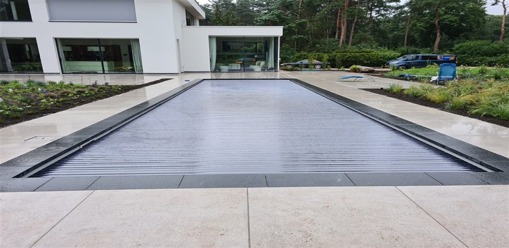 Gesloten lamellenafdekking met donkere rand en een witte villa op de achtergrond.
