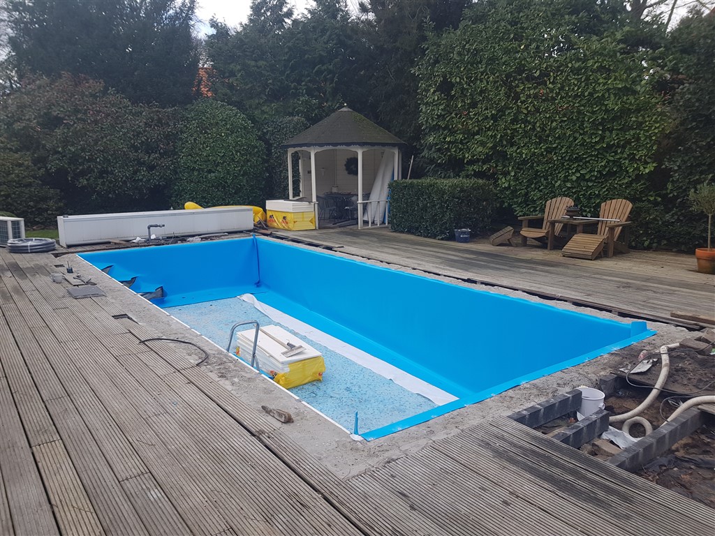 Blauwe folie op de wanden, de bodem nog in oud mozaïek, met tuinhuisje en vlonder.